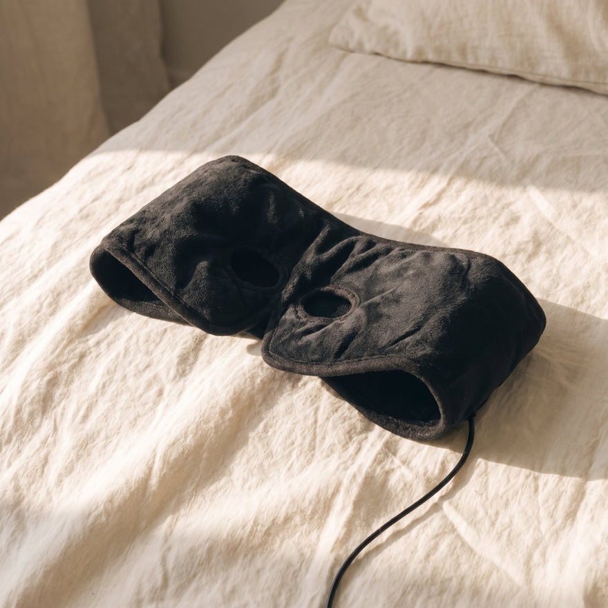 The Eyes Open mask folded on a bed in afternoon light, ready to use